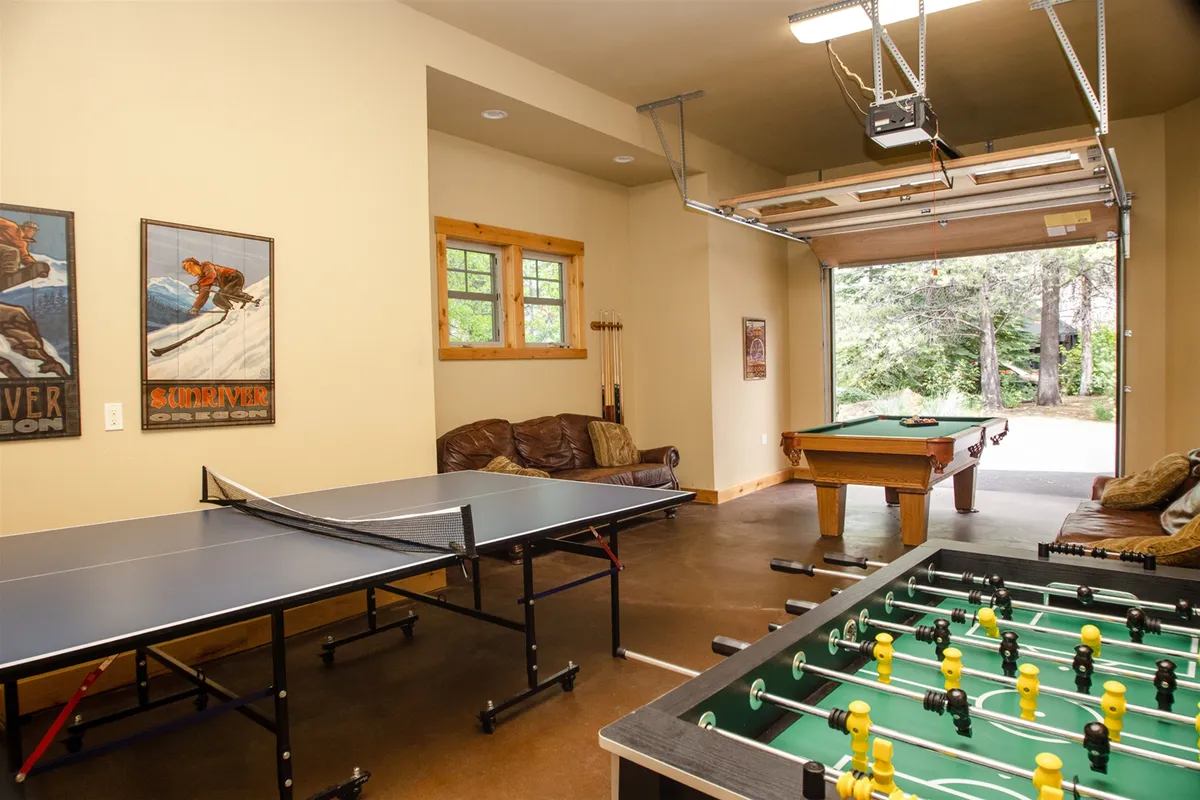 A vibrant entertainment space featuring a ping pong table, foosball table, pool table, a sofa, and wall art. The room is set up for active play and socializing, with multiple game options and inviting relaxation areas. The decor and layout reinforce the lively, communal vibe described in the content.