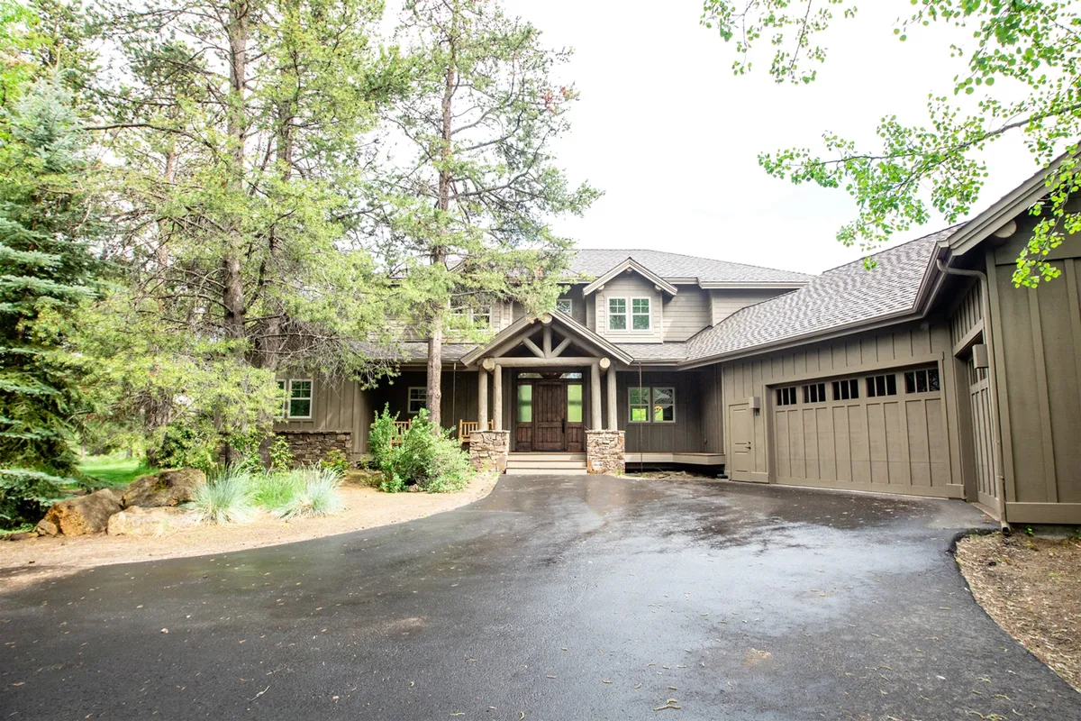 A welcoming shot of a home's front porch with stone accents, large windows, and a driveway. The scene suggests both a grand entrance and opportunities for gathering on the porch, enjoying outdoor meals, or simply taking in the garden and surroundings.